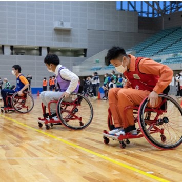 車椅子に乗ってリレー競争をする人の写真