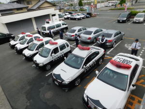 写真：駐車場代に並んでいる数台のパトカーと警察官たち